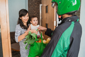 woman and baby shopping grocery online and delivered by courier at home