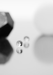 Abstract composition, marble in the foreground is reflected on a glossy surface, blurred a second marble and other geometric shapes, monochromatic color treatment.