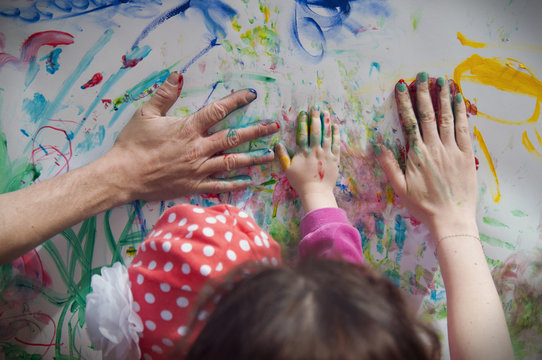Family draws hands covered in paint. Father, mother and child leave hand prints.