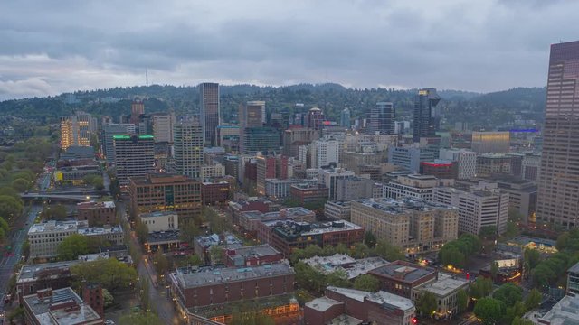 Aerial Timelapse Pans Across Downtown Portland Oregon during Light Drizzle, as Rain Clouds Pass Overhead and And City Lights Begin to Turn on After Sundown