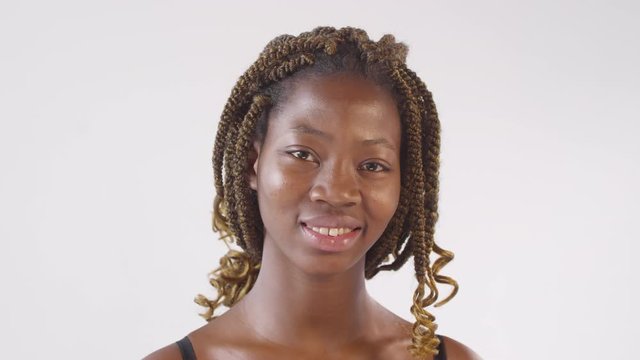 Portrait shot of beautiful black woman with dreadlocks smiling for camera and posing against white background