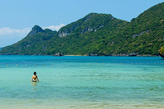 An unrecognizable woman swimming in the sea in the Ang Thong Marine National Park near Koh Samui in Thailand.  Tourism background image. 