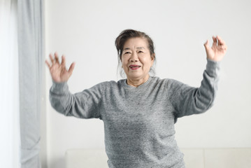 Asian senior woman doing exercise and dancing at home, stay home lifestyle concept. Motion blur.