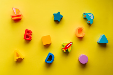 Top view on children s toys on a yellow background. Children's toys on the table. concept for advertising toys for children. Copy space children's toy.