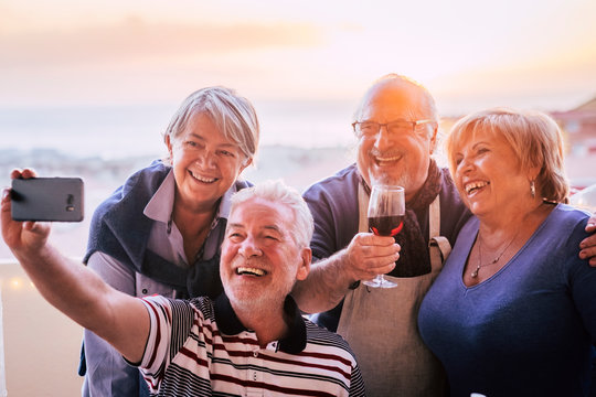 Group of happy friends senior people have fun together with social contact doing selfie with a smart phone - mature celebrate in outdoor - retired lifestyle and men women smile and laugh in friendship