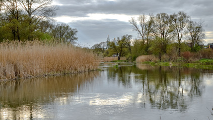 The river goes into the distance with village houses and a Church against the grey sky