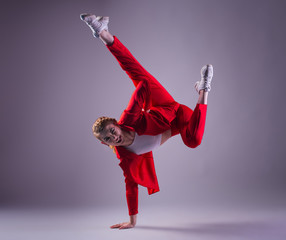 Teenage girl in red suit dancing hip-hop on grey background