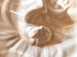 surface of freshly whipped Dalgona coffee (korean beverage made by whipping instant coffee powder, sugar and hot water) close up