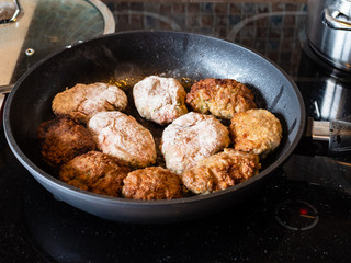 many russian Kotleta (minced beef steaks breaded with flour) in hot pan on ceramic stove at home kitchen