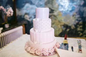 White and pink mastic covered wedding cake stands on a table at the restaurant