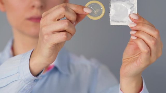 Female hands demonstrating condom before camera, safe sex, contraception