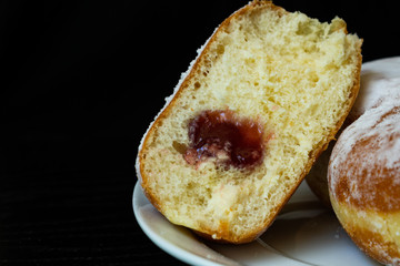 Donuts with sugar on a white plate and black background. Donuts with jam.