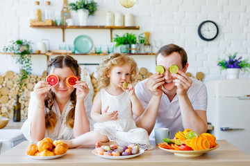Happy family in the kitchen. Healthy food at home. Choose between fruit or cookies. The concept of healthy eating.