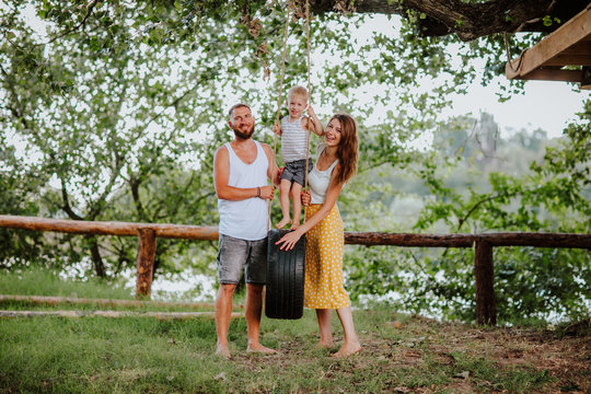 Family On The Nature Countryside Swinging On Tire Swing In The Summer