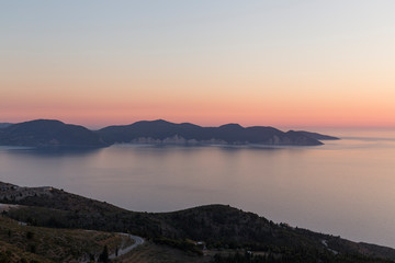 sunset at sea seen from a viewpoint in Kefalonia, Greek island, the water is calm and the sky takes on orange tones