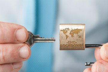 End of lockdown due to covid-19 concept image: business man in blue shirt and tie use a key to open...