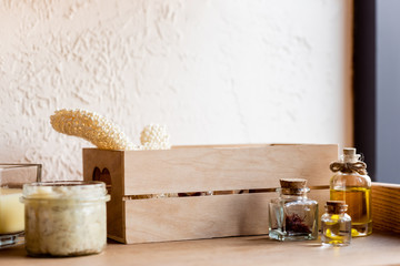 wooden box, with loofah, bottles of oil, clay mask in jar and candle on shelf