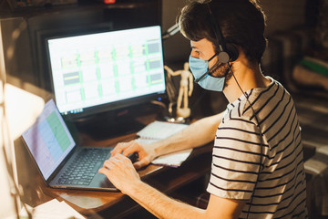 Fototapeta na wymiar man wearing a protective mask working at home at the computer during quarantine virus epidemic disease