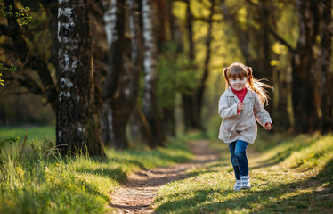 Little girl runs in the park and laughs
