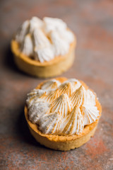 Creamy cake decorated with meringue cream on the rustic background. Selective focus. Shallow depth of field.
