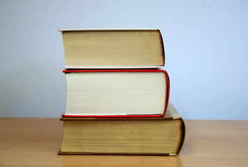 Three books laid by side on the wooden background