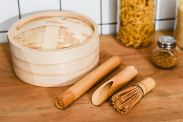 Fototapeta na wymiar selective focus of bamboo steamer near cooking utensils and jars with dried pasta