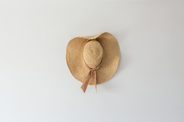 Fototapeta na wymiar Headdress straw hat, beige panama hanging on the wall in a horizontal position.