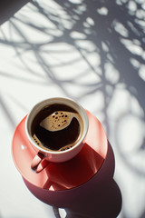 aromatic black coffee in a pink cup in the morning on a white background with shadows
