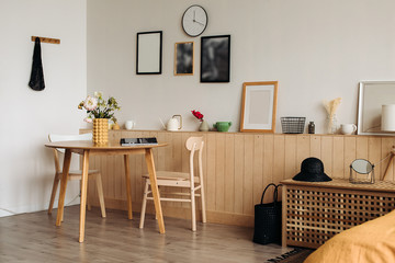 Wooden dining table in a bright home interior. On the table are peonies in a designer yellow vase .