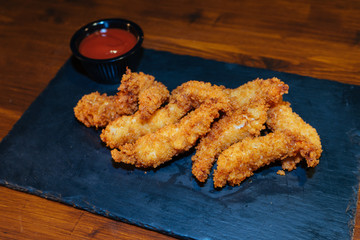 chicken or breaded fish, deep-fried with sauce on a black tray in a roadside cafe