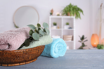 Fresh towels and eucalyptus branches on grey wooden table in bathroom. Space for text