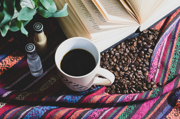 Still life of a nice warm cup of coffee, surrounded with coffee beans a good book and little...