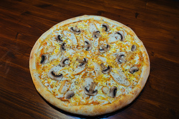 Italian pizza with mushrooms and cheese on a wooden table