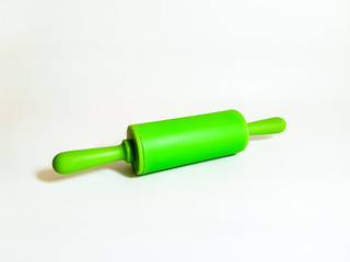 Kitchen utensils. Bright green rolling pin on a white background. 