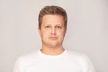 Fototapeta premium Portrait of a european type man adult young in a white t shirt on an isolated background