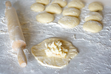 dough piece for pies with cabbage and potatoes on a white table with flour