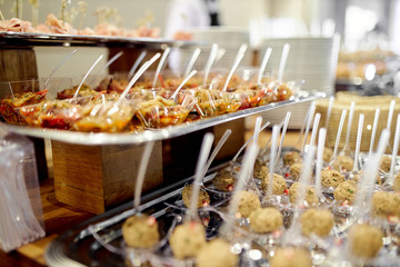 buffet snacks, canapes placed on trays. Snacks with meat, fruits, cheeses with an individual spoon for each guest