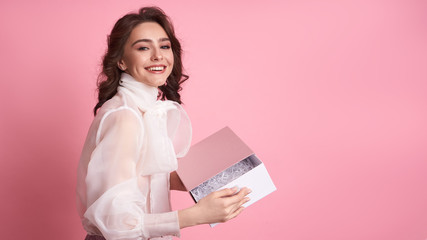  Young girl holding a pink box on a pink background