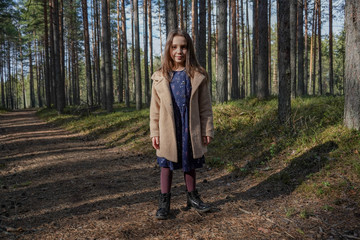 
little girl in the forest. On a forest road among the pines.