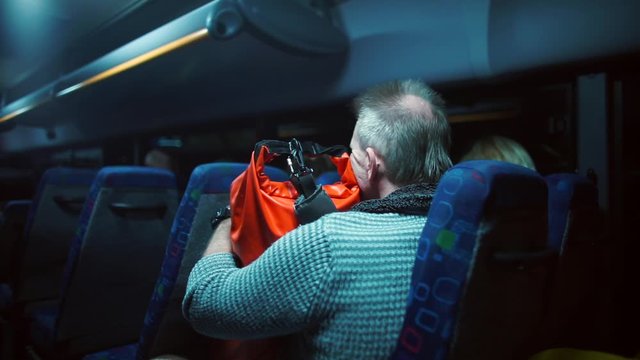 Delivery of humanitarian aid. A man rides a bus with an orange backpack at night. Gratis help, assistance. 