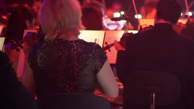 Musicians play the violin. Instruments on stage with a Symphony orchestra. In the dark with lanterns. Live performance.