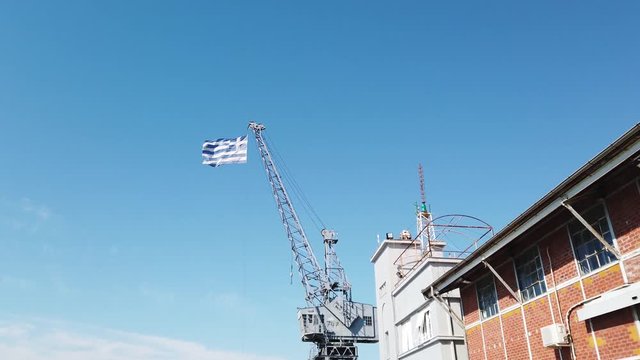 4k clip of the Greek flag waving on the top of a crane in  port of Thessaloniki in Greece with clear sky 