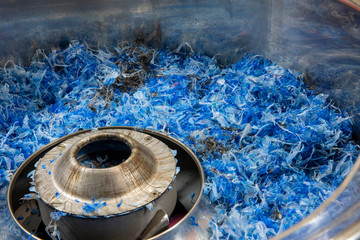Blue plastic recycled parts material made of blue colored  bottle caps in a grinder ready to be...