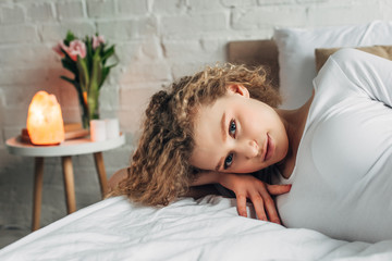 attractive woman lying on bed in bedroom with Himalayan salt lamp