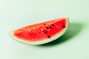 A piece of red juicy watermelon lies on a green background. Copy space