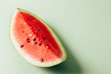Fototapeta na wymiar A piece of red juicy watermelon lies on a green background. Copy space