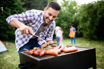 Handsome male preparing barbecue, grill outdoors for friends
