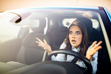 Obraz na płótnie Canvas Woman is driving her car very aggressive and gives gesture with her fist. Angry female driver. Negative human emotions face expression. Furious woman stucked in traffic jam