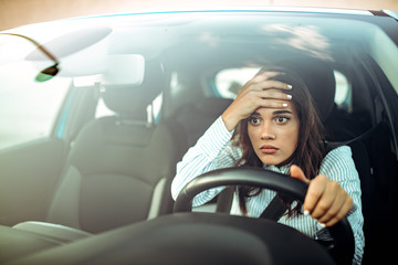 Angry woman driving a car. The girl with an expression of displeasure is actively gesticulating...