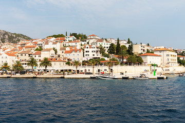 Fototapeta na wymiar Hvar town on Hvar island, view from the sea on a sunny day in the summer blue sky. Clear adriactic water, the south mediterranean coast of Croatia Europe. Beautiful landscape with greenery